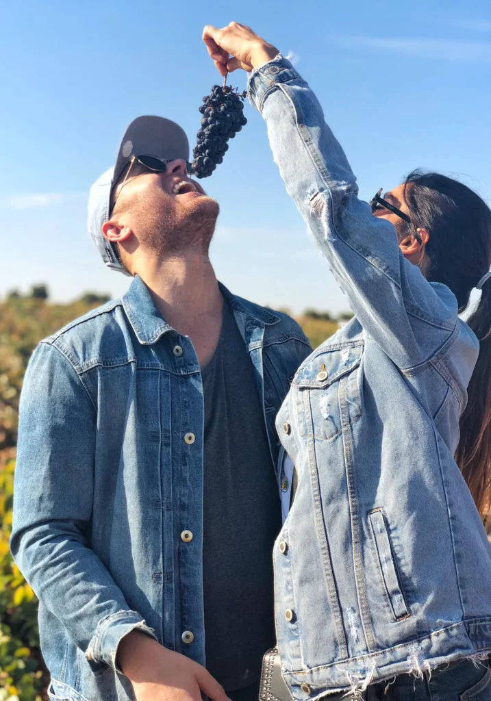 couple in Spain with a bunch of grapes at vineyard colorful wines